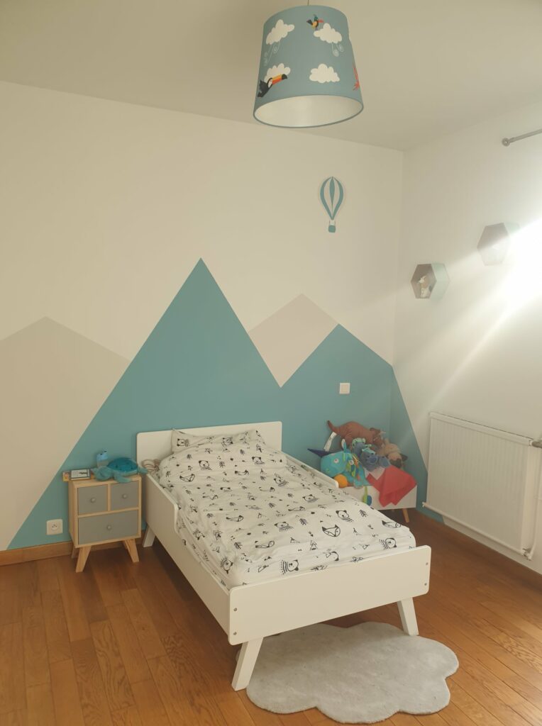 chambre-enfant-motif-montagnes Chambre d'enfant colorée avec murs bleus décorés de motifs de montagnes et éclairage ludique